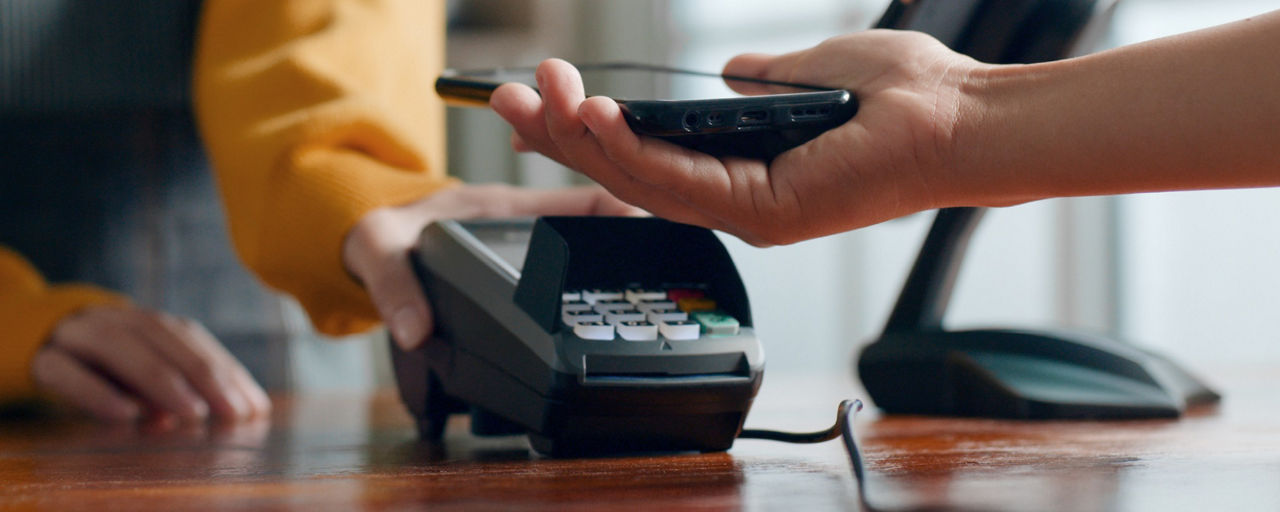 Smartphone wird zum Bezahlen an Terminal gehalten