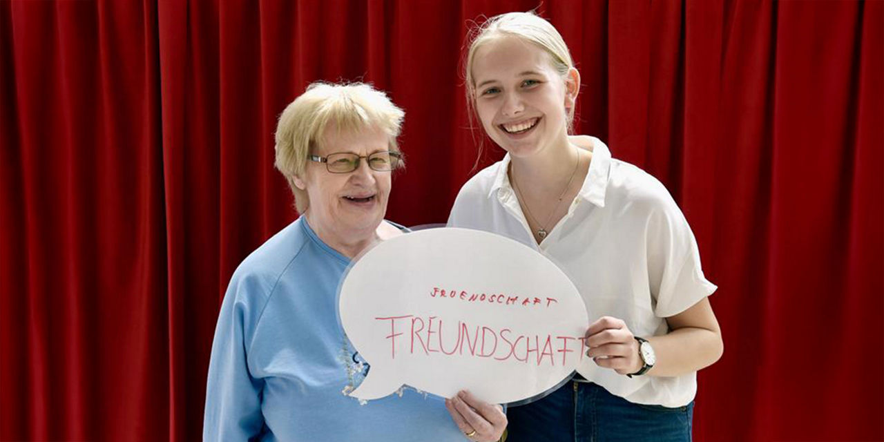 Generationsübergreifende Freundschaft: Junge Frau steht neben älterer Dame und freut sich über die gemeinsame Zeit