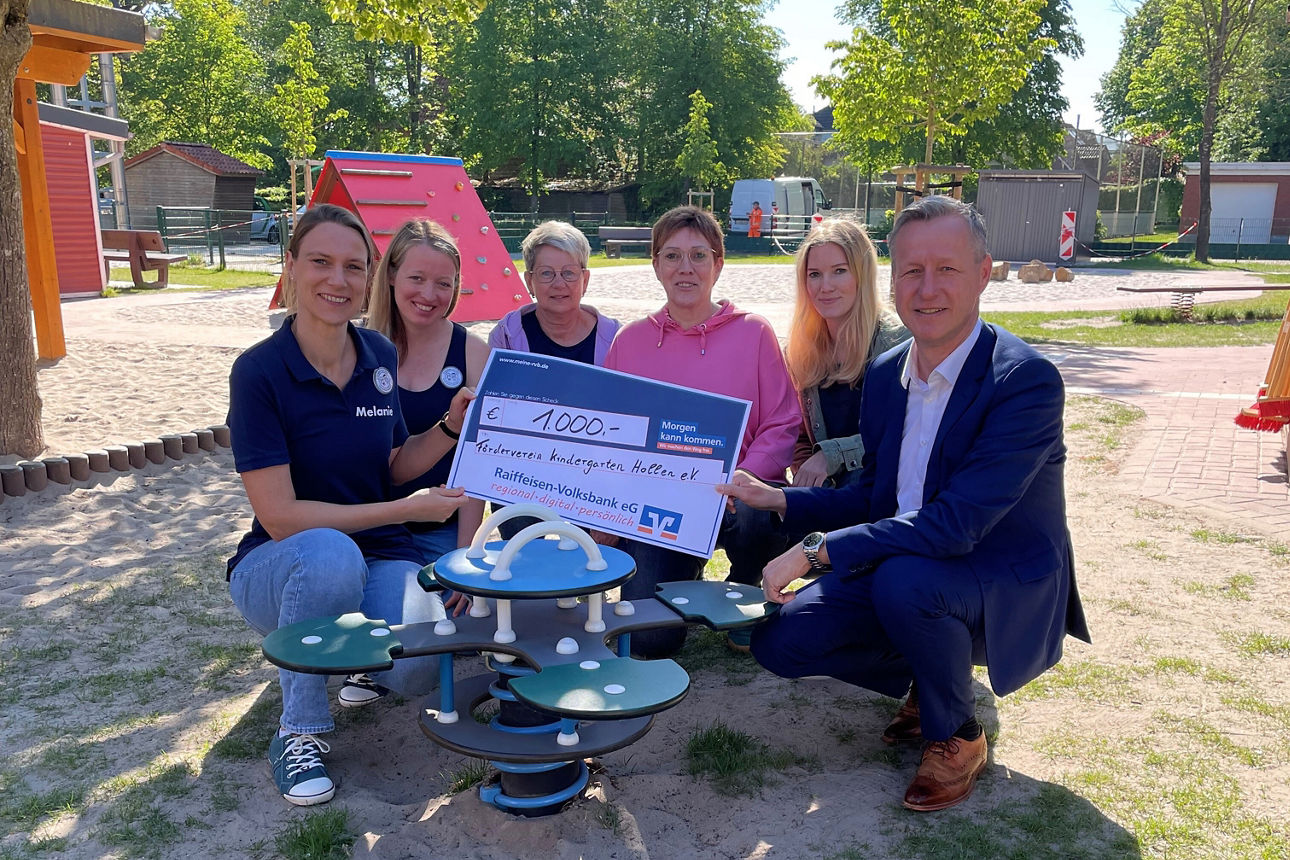 Sechs Personen bei symbolischer Scheckübergabe im Kindergarten Hollen