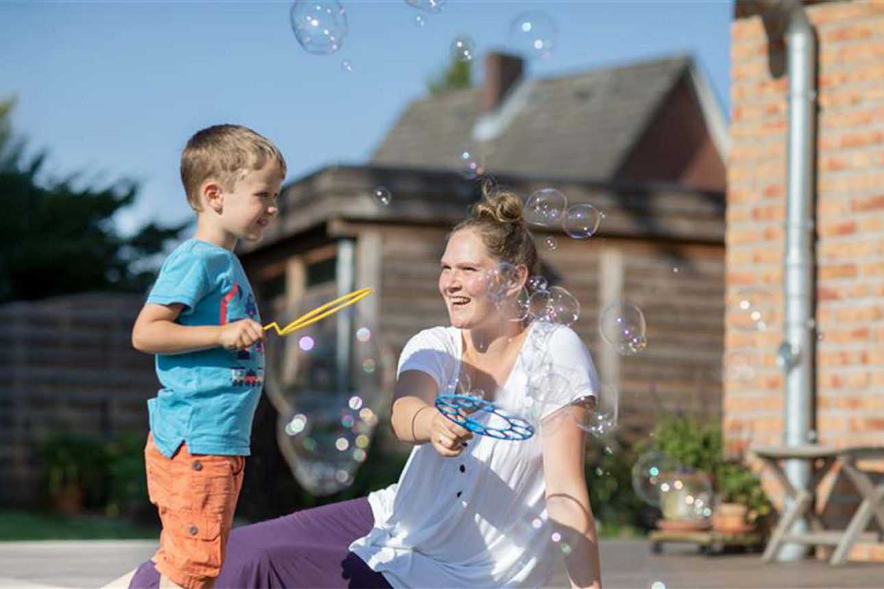 Mutter pustet Seifenblasen mit ihrem Sohn auf der eigenen Terrasse