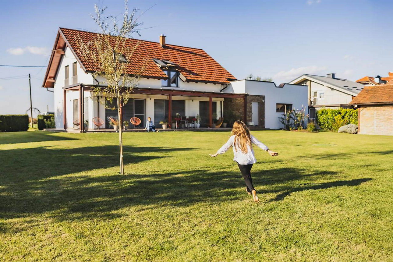 Junges Mädchen läuft Barfuß durch den Garten des Einfamilienhauses