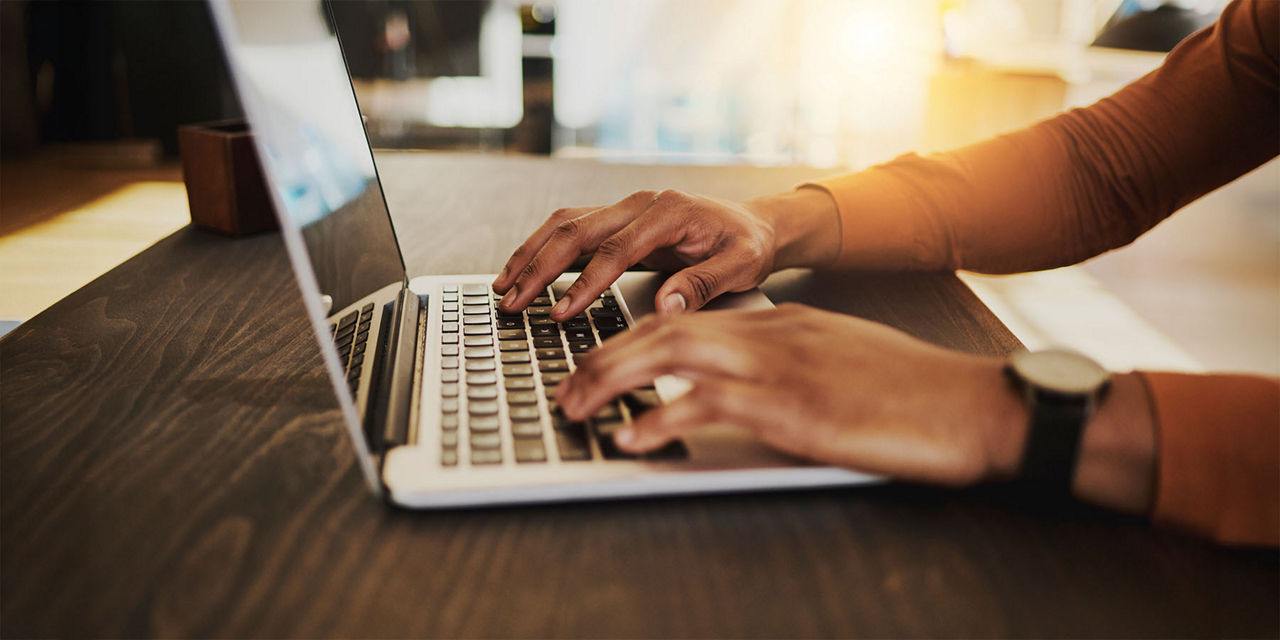 Person tippt auf einer Tastatur eine Auslandsüberweisung ein