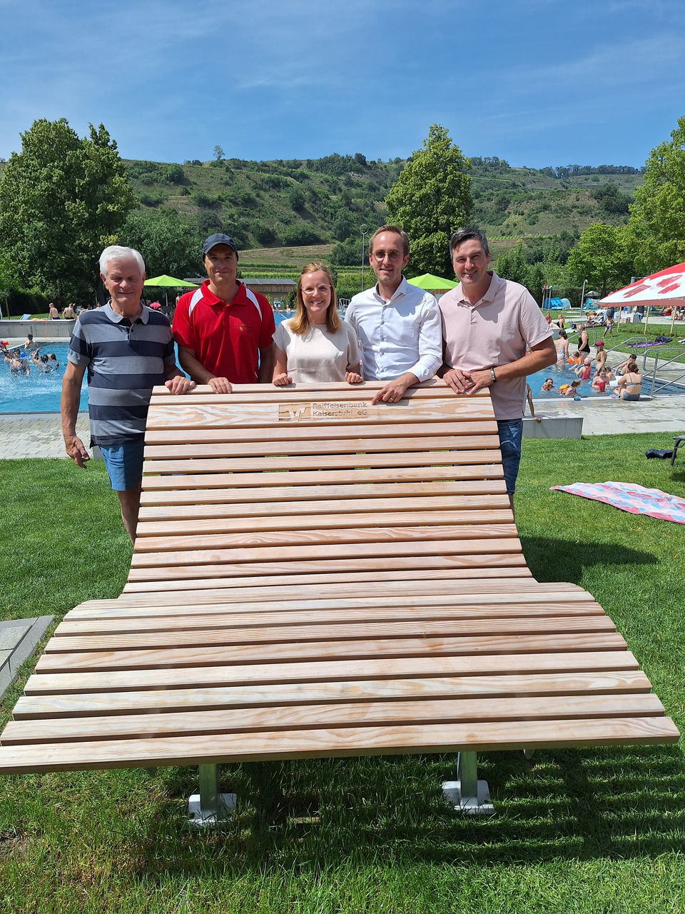 Bürgermeister Benjamin Bohn und Ortsvorsteher Henrik Roland Leininger stehen hinter einer großen Liege im Schwimmbad