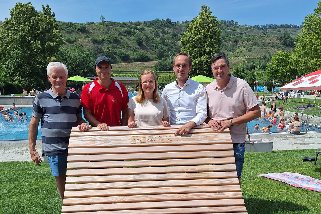 Bürgermeister Benjamin Bohn und Ortsvorsteher Henrik Roland Leininger stehen hinter einer großen Liege im Schwimmbad