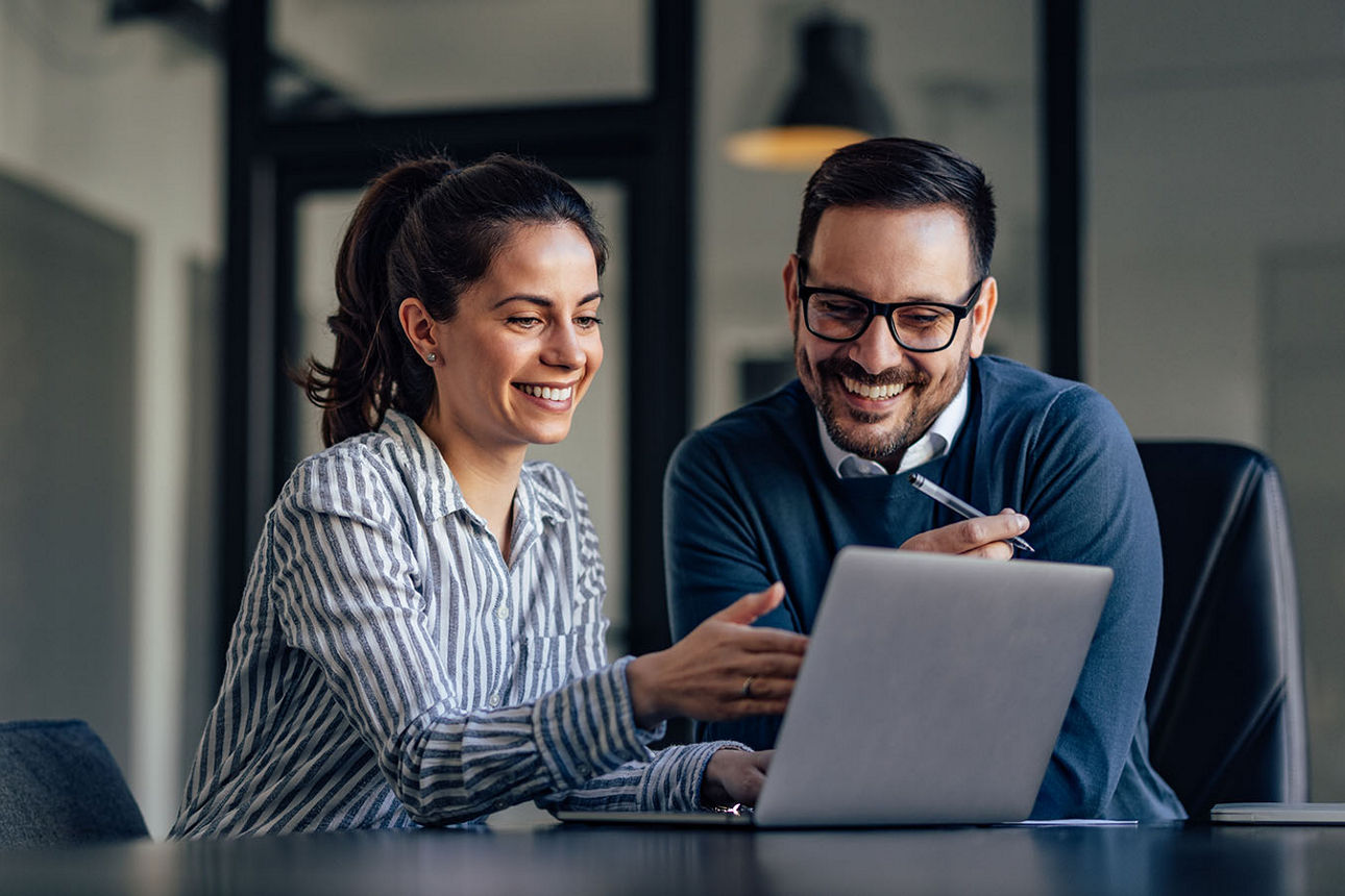 Frau und Mann sitzen am Laptop