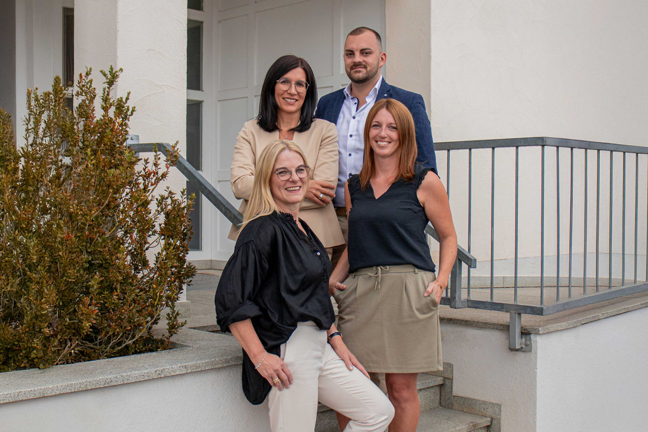 Ein Team von Immobilienfachleuten steht vor einer Ausstellung für ein Immobiliencenter.