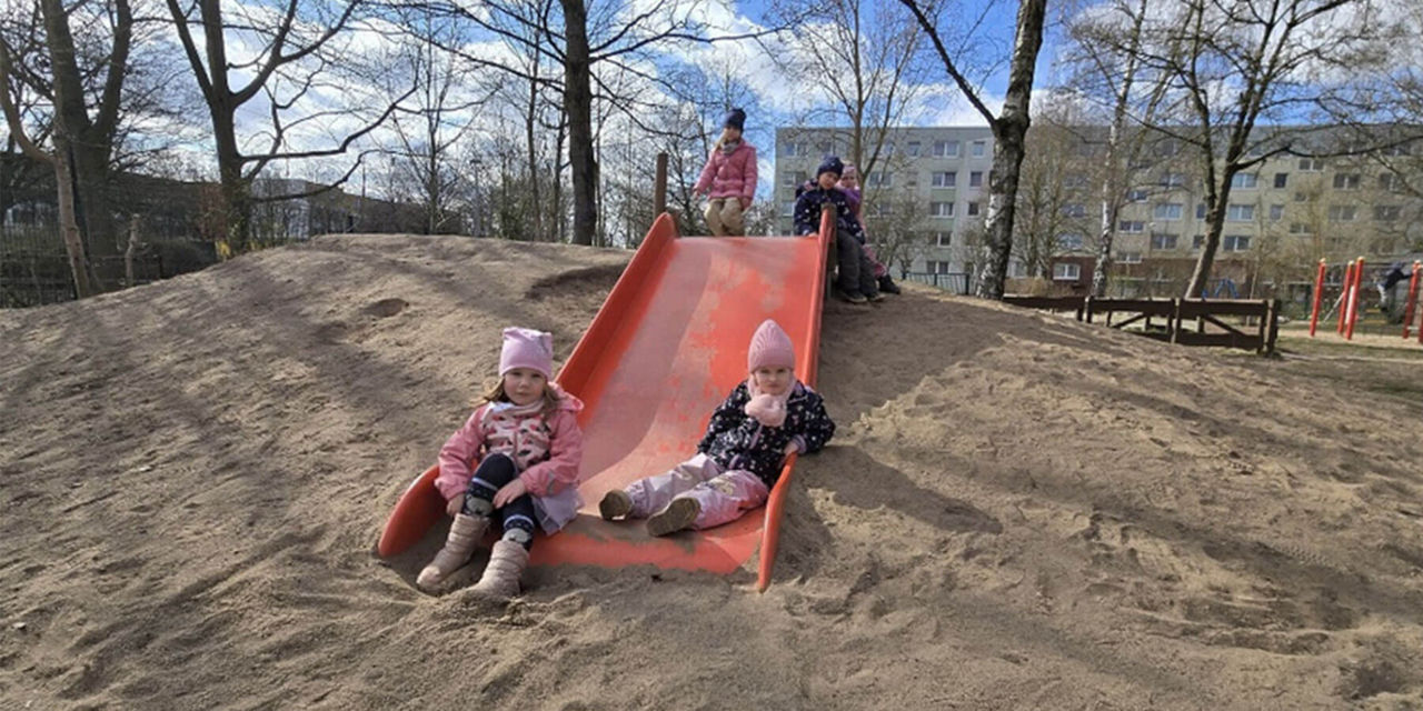 Kinder sitzen auf einer großen Rutsche