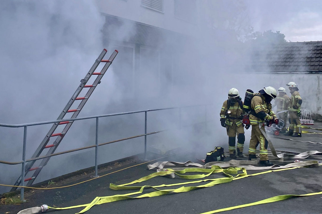 Vier Feuerwehrleute stehen vor der verrauchten Volksbank-Geschäftsstelle in Drabenderhöhe.