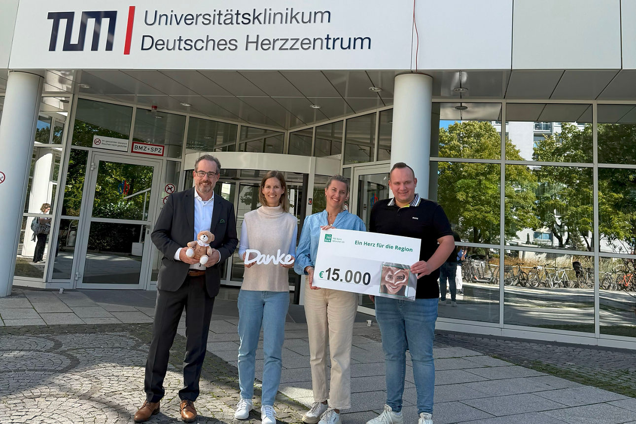 Vier Personen stehen von dem Universitätsklinikum Deutsches Herzzentrum in München. Der Mann links hält einen Teddybären in der Hand, die Frau daneben einen Danke-Schriftzug. Daneben halten eine Frau und ein Mann einen Spendencheck in Höhe von 15.000 Euro