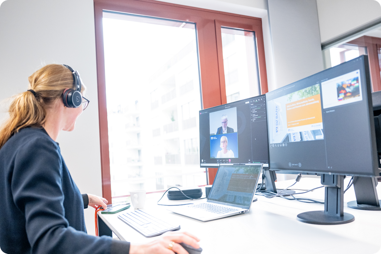 Eine Frau sitzt vor Monitoren und schaut sich das Online Seminar an