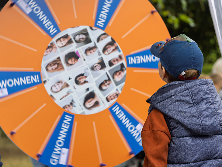 Junge steht gespannt vor einem sich drehenden Glücksrad