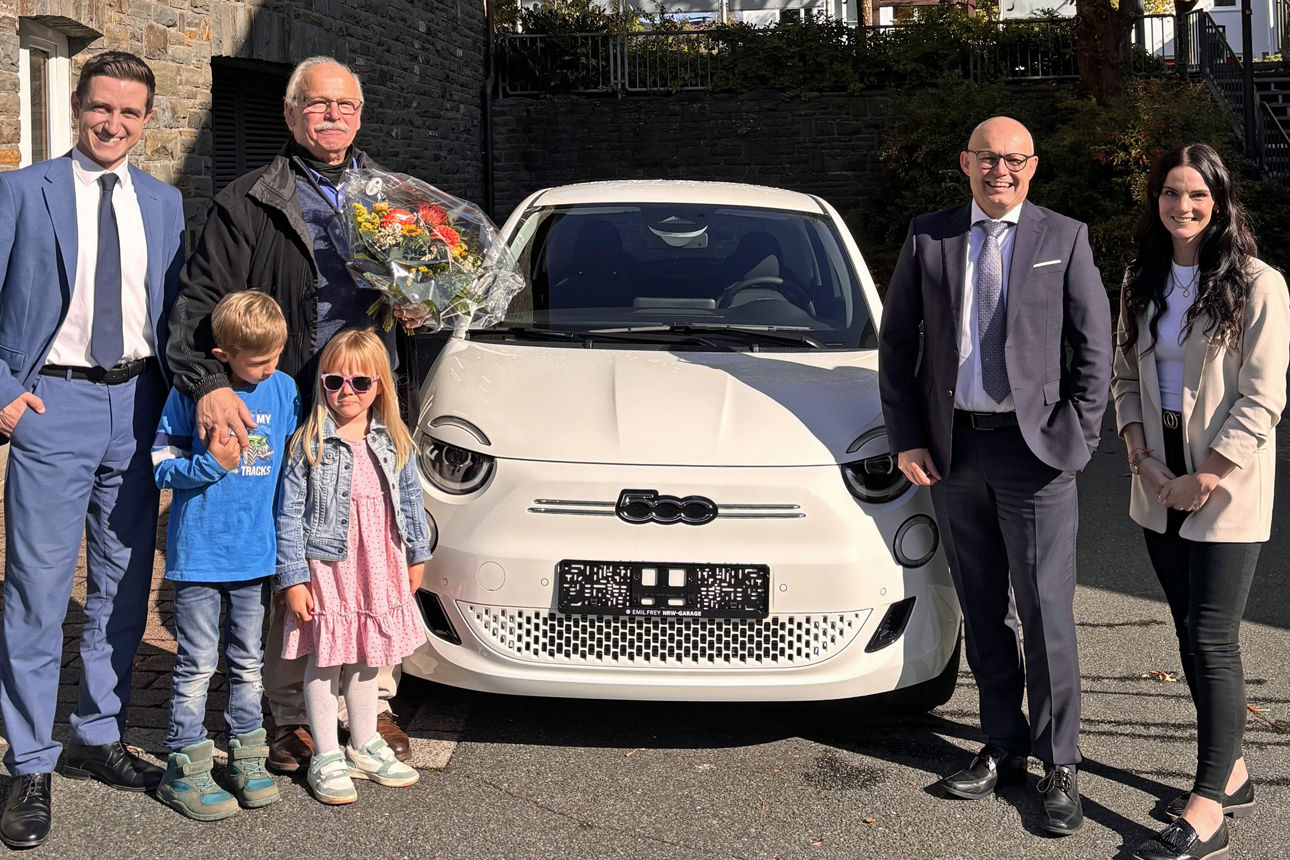 Gewinner Karl-Heinz Altmann steht mit seinen Enkeln und drei Volksbank-Mitarbeitern vor seinem neuen Auto.