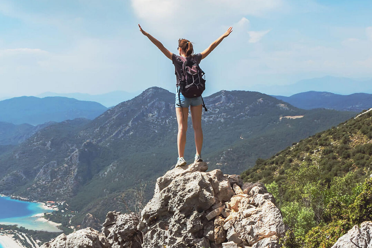 Junge Frau steht auf einem Berg und schaut in die Ferne