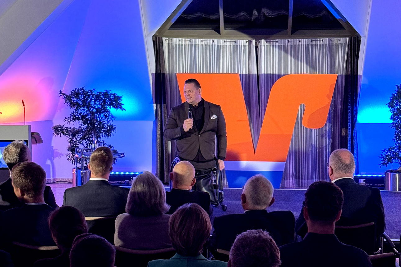 Florian Sitzmann auf der Bühne im Forum der Volksbank Oberberg in Wiehl während seines Vortrags beim UnternehmerForum. Im Vordergrund sind Köpfe des Publikums zu sehen.