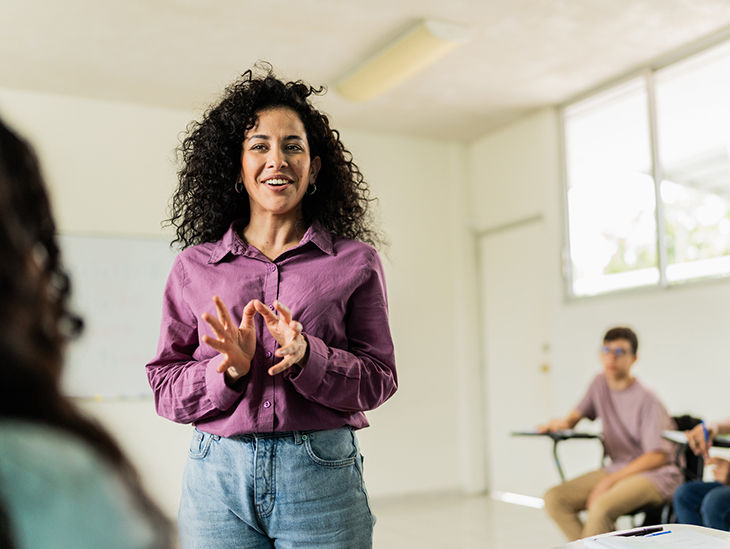 Frau in Bluse hält einen Vortrag und interagiert mit ihren Teilnehmern