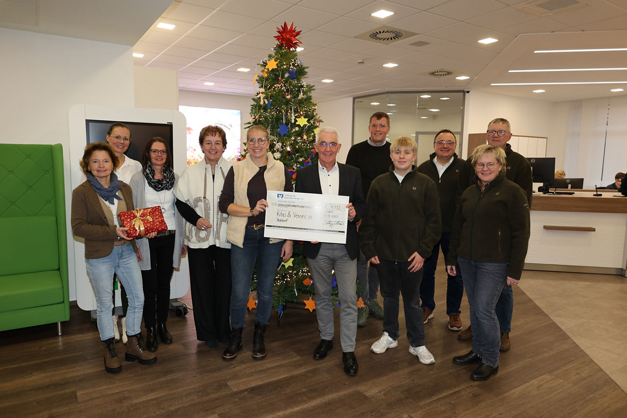 Mehrere Personen haben sich zu einem Foto aufgestellt vor einem großen Tannenbaum