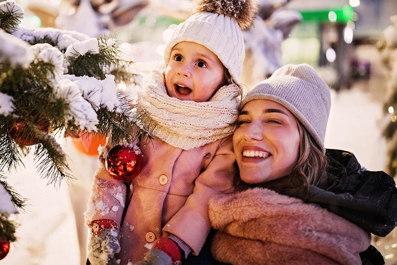 Mutter und Tochter stehen vor einem Weihnachtsbaum