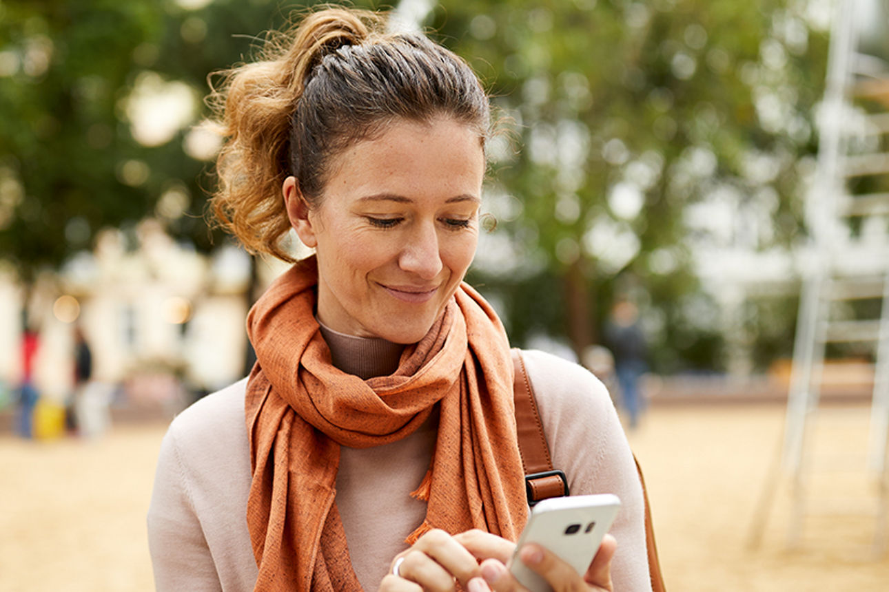 Frau mit Handy in der Hand auf dem Spielplatz