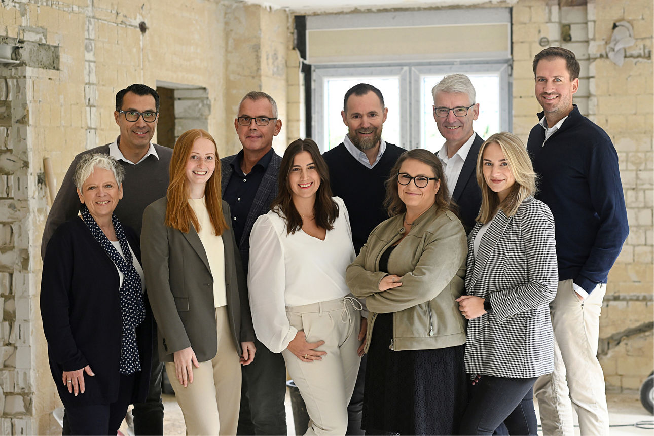 Mann und Frau im Gespräch mit Bankberaterin vor dem Rohbau einer Immobilie