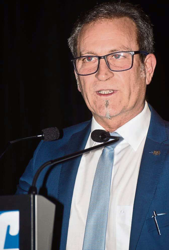 Ein Mann in Anzug und Brille spricht auf einem Podium