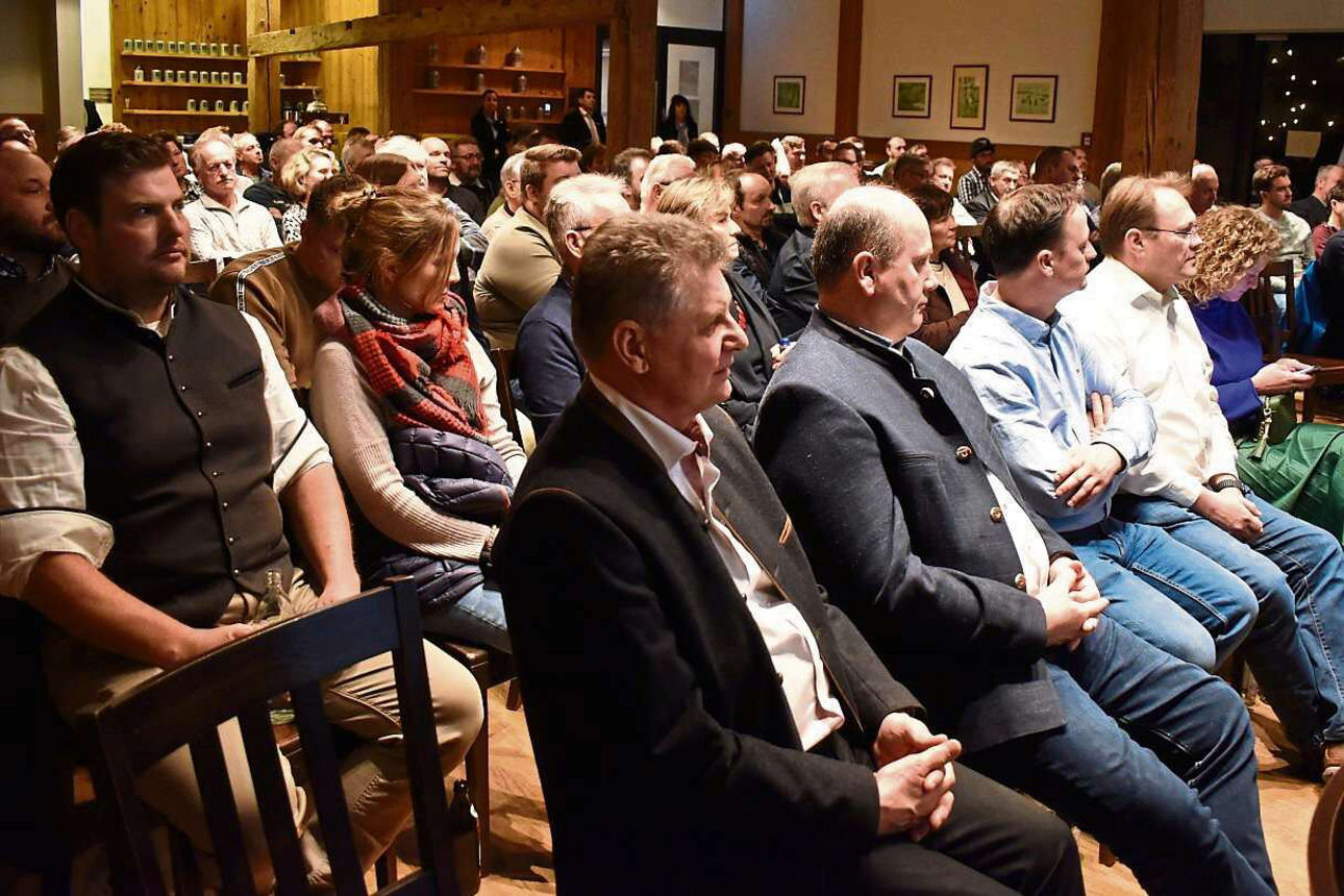 Viele Menschen, die in Reihen auf Stühlen sitzen und nach vorne auf die Bühne blicken