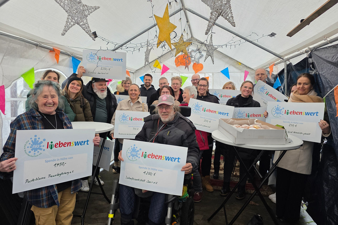 Eine Gruppe von Menschen steht zusammen und hält Spendenschecks in den Händen.