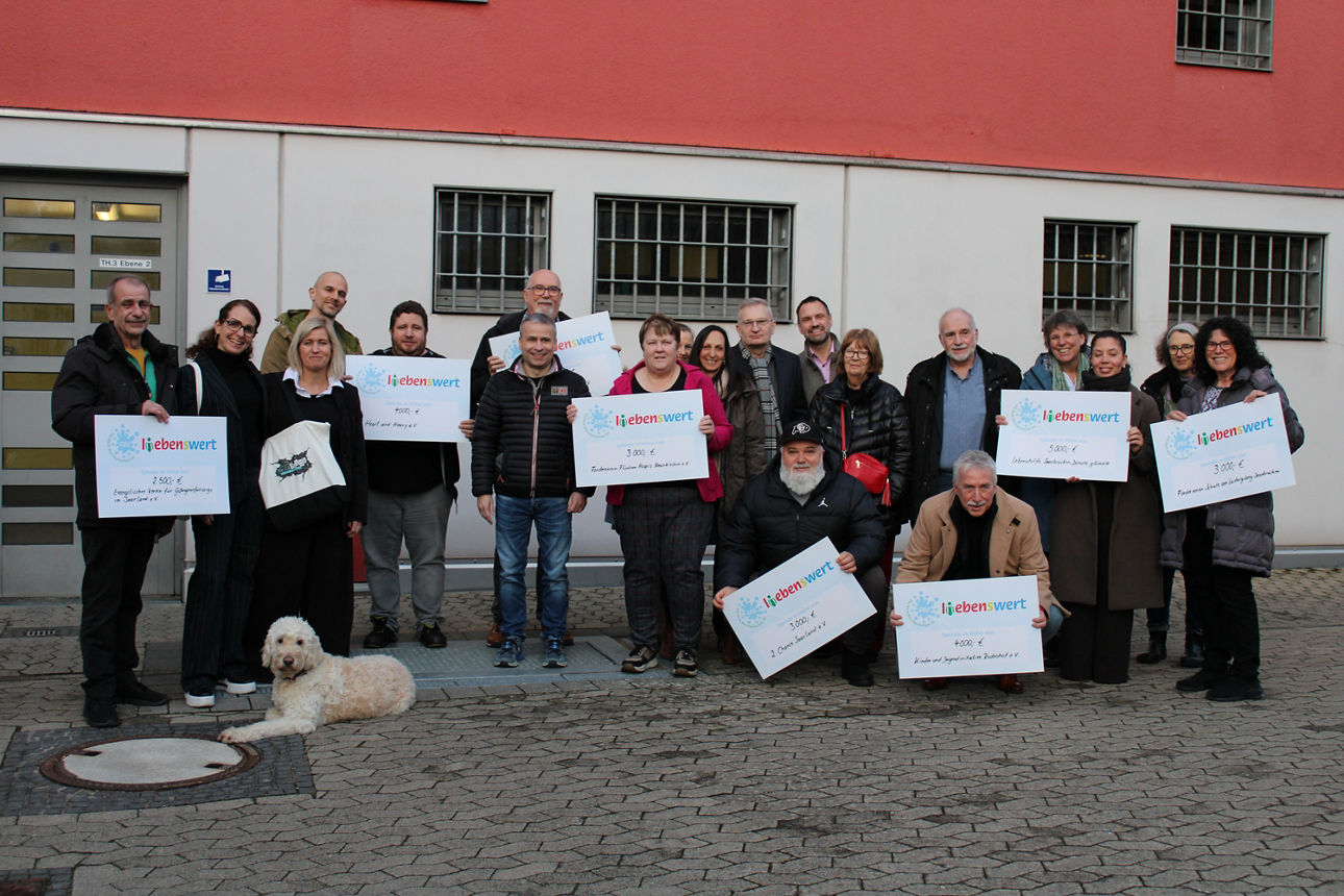 Mehrere Menschen halten symbolische Schecks in den Händen 