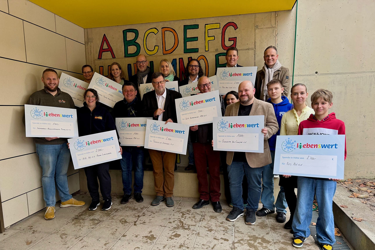 Eine Gruppe von Menschen steht zusammen und hält Spendenschecks in den Händen.