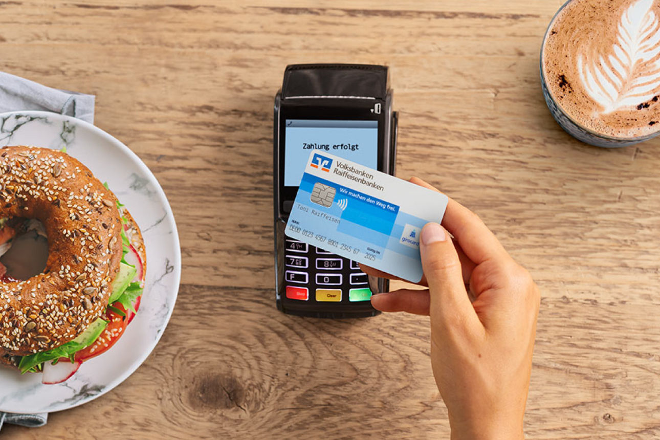 Eine blau weiße Karte wird an ein Kartenterminal gehalten