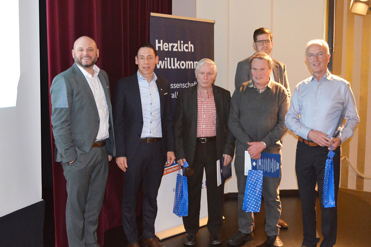 Geehrte Personen stehen nebeneinander vor einer Wand