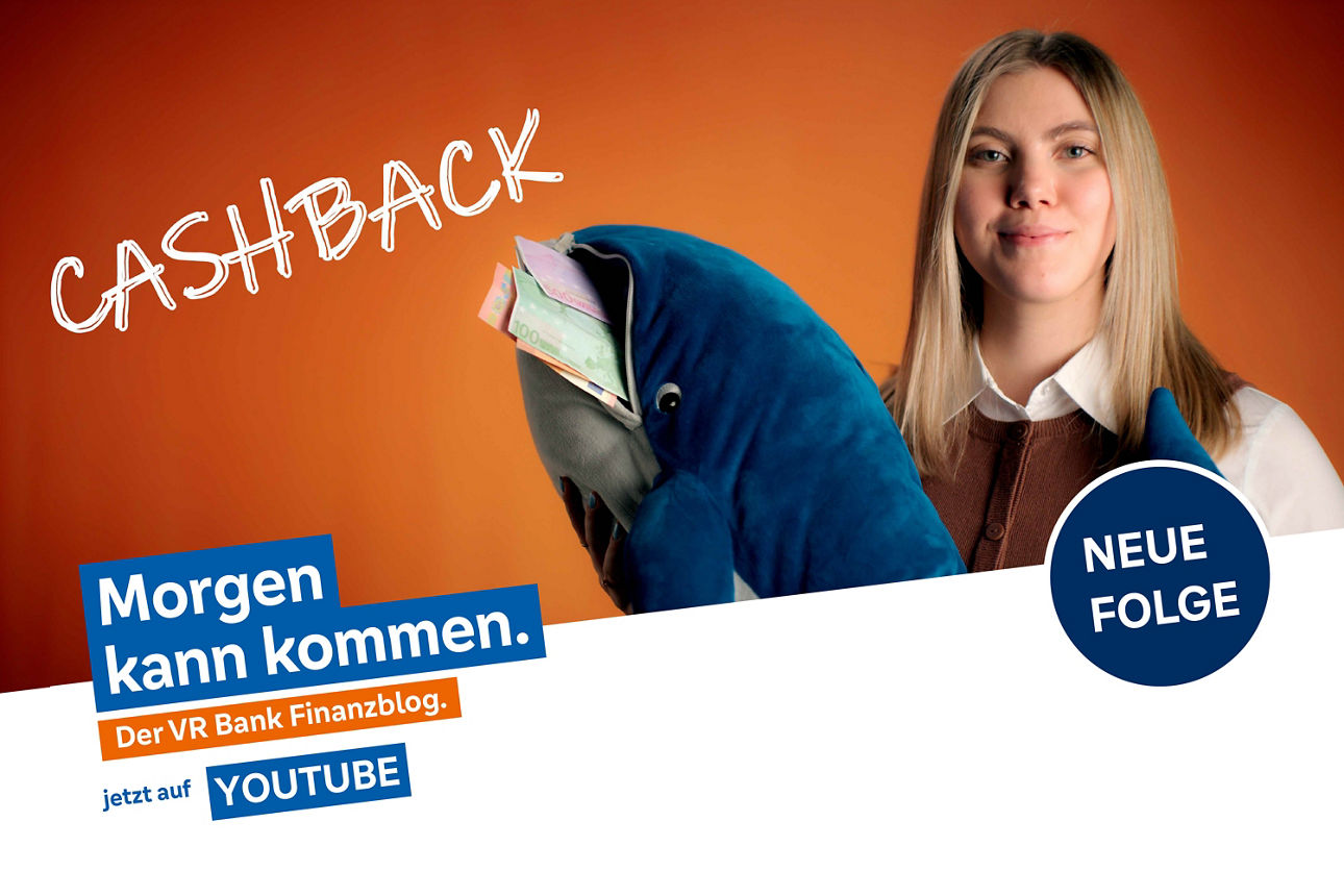 Frau mit blondem Haar hält einen Stoffhai mit Zetteln im Maul hoch.