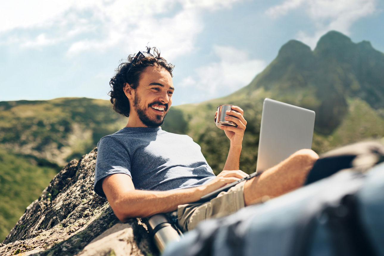 Man sitzt auf einem Berg mit seinem Laptop