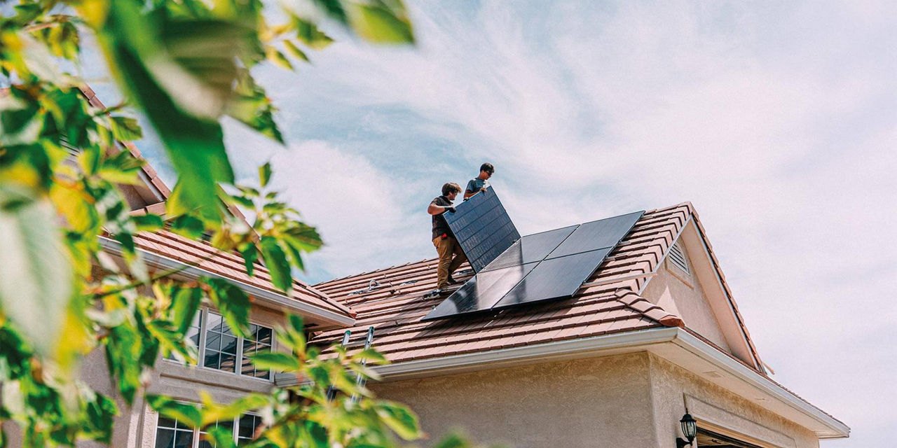 Zwei Handwerker montieren eine Solaranlage auf einem Hausdach