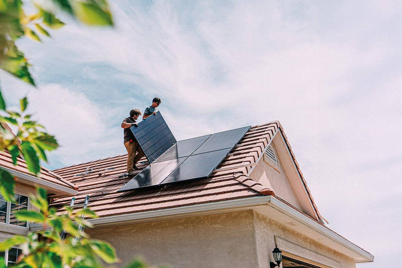 Zwei Handwerker montieren eine Solaranlage auf einem Hausdach
