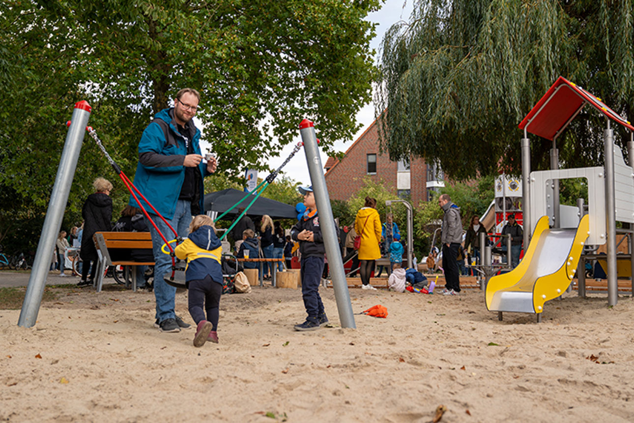 Kinder und Eltern spielen gemeinsam auf Spielplatz