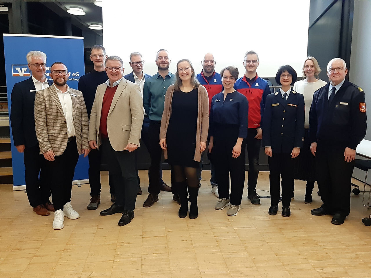 Gruppenfoto mehrerer Personen, die in einer Veranstaltungsumgebung nebeneinander stehen.