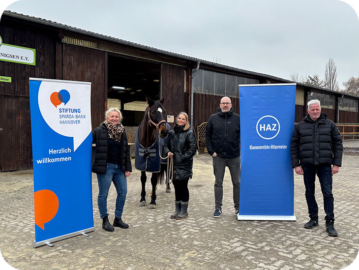 Eine Gruppe von Personen steht vor einer Reithalle