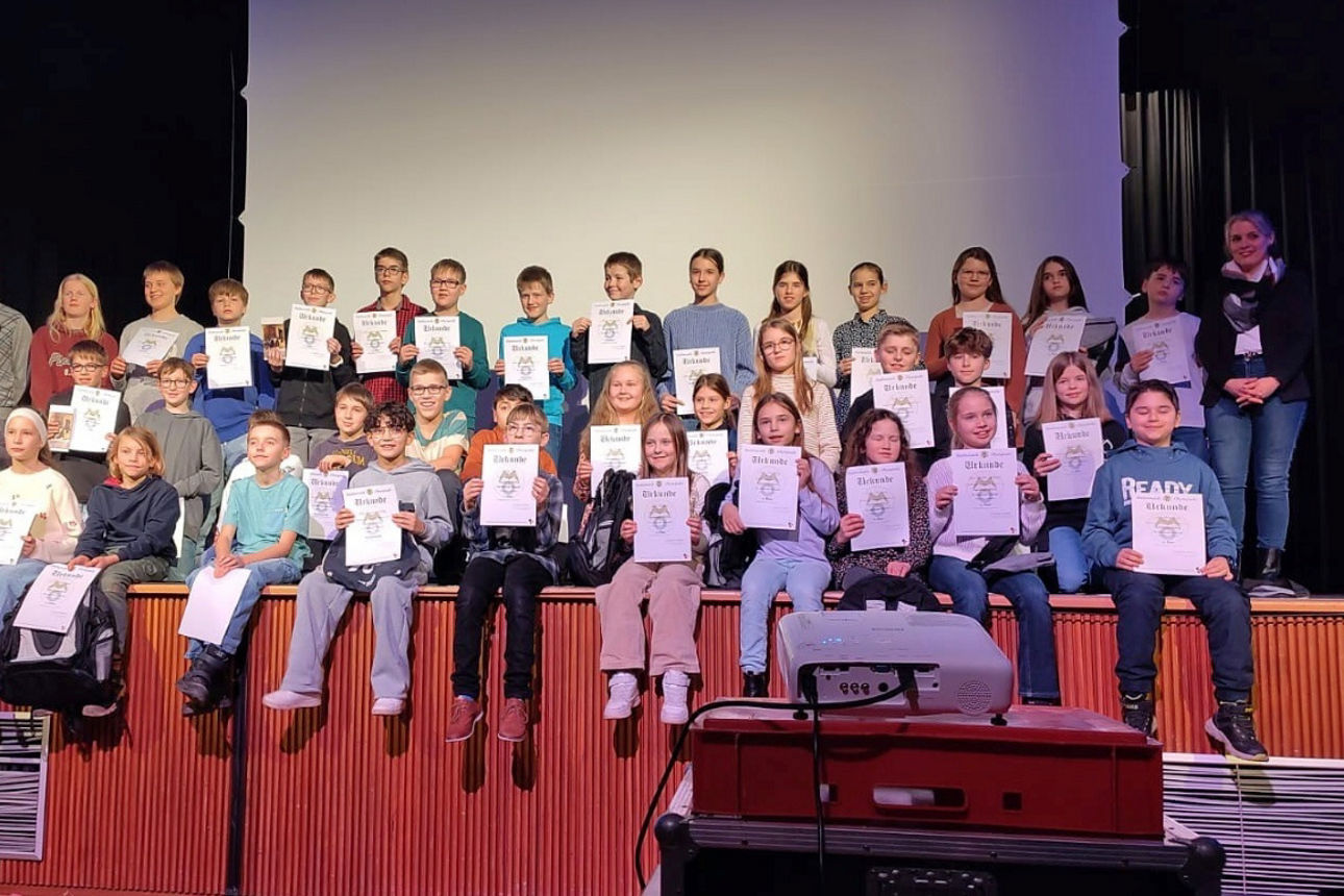Gruppenfoto der ausgezeichneten Teilnehmerinnen und Teilnehmer der 65. Mathematik-Olympiade auf der Bühne des Hollenberg-Gymnasiums Waldbröl mit ihren Urkunden.