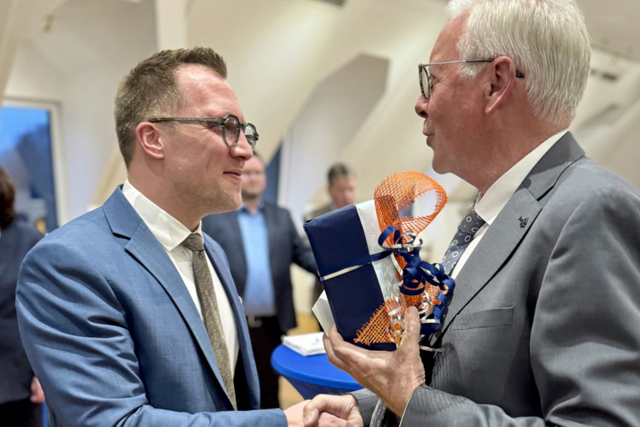 Dr. Udo Meyer überreicht Andreas Neumann bei einer Feierstunde in der Hauptstelle ein Geschenk und gratuliert ihm per Handschlag zum 40. Geburtstag.