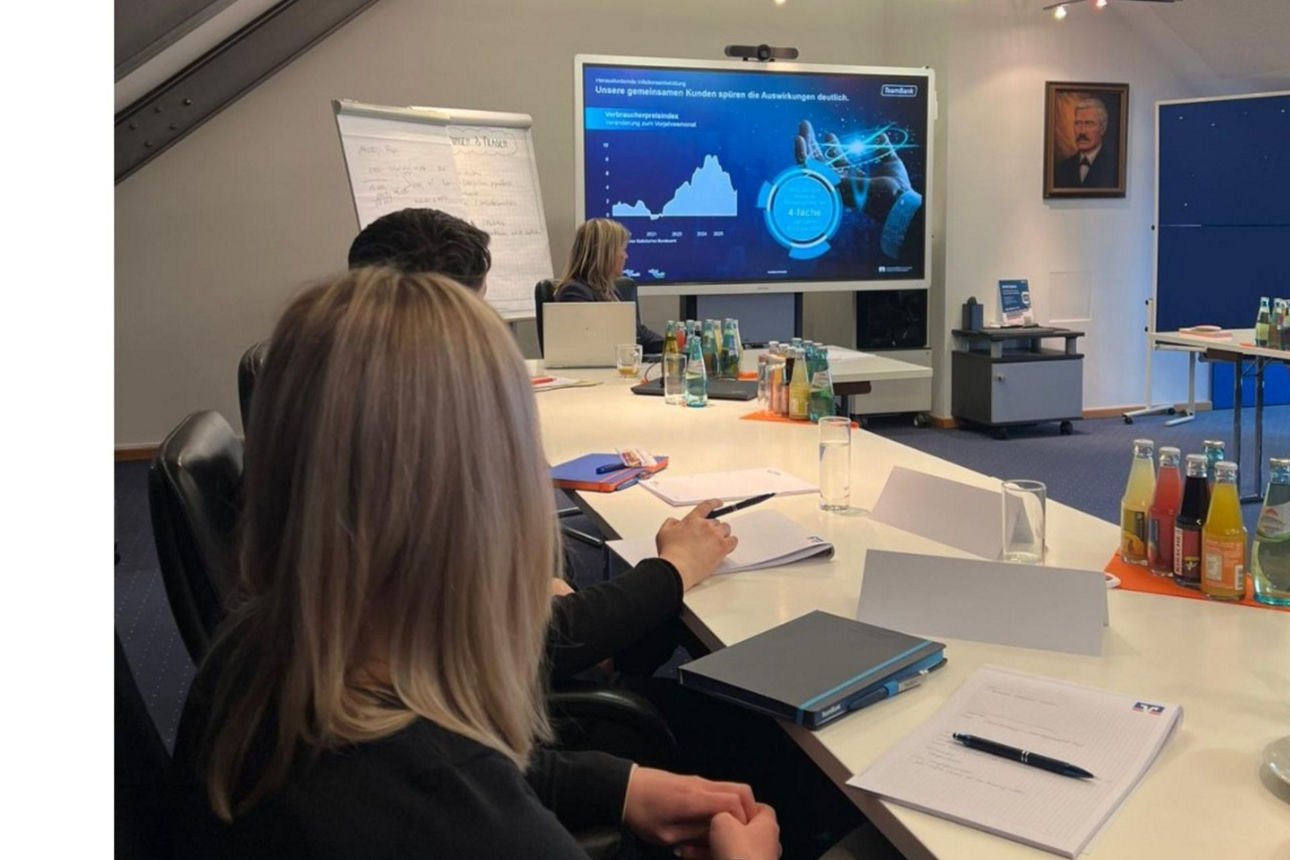 Workshop-Szene - Blick auf Hinterköpfe von am Tisch sitzenden Auszubildenden, die auf einen Bildschirm schauen