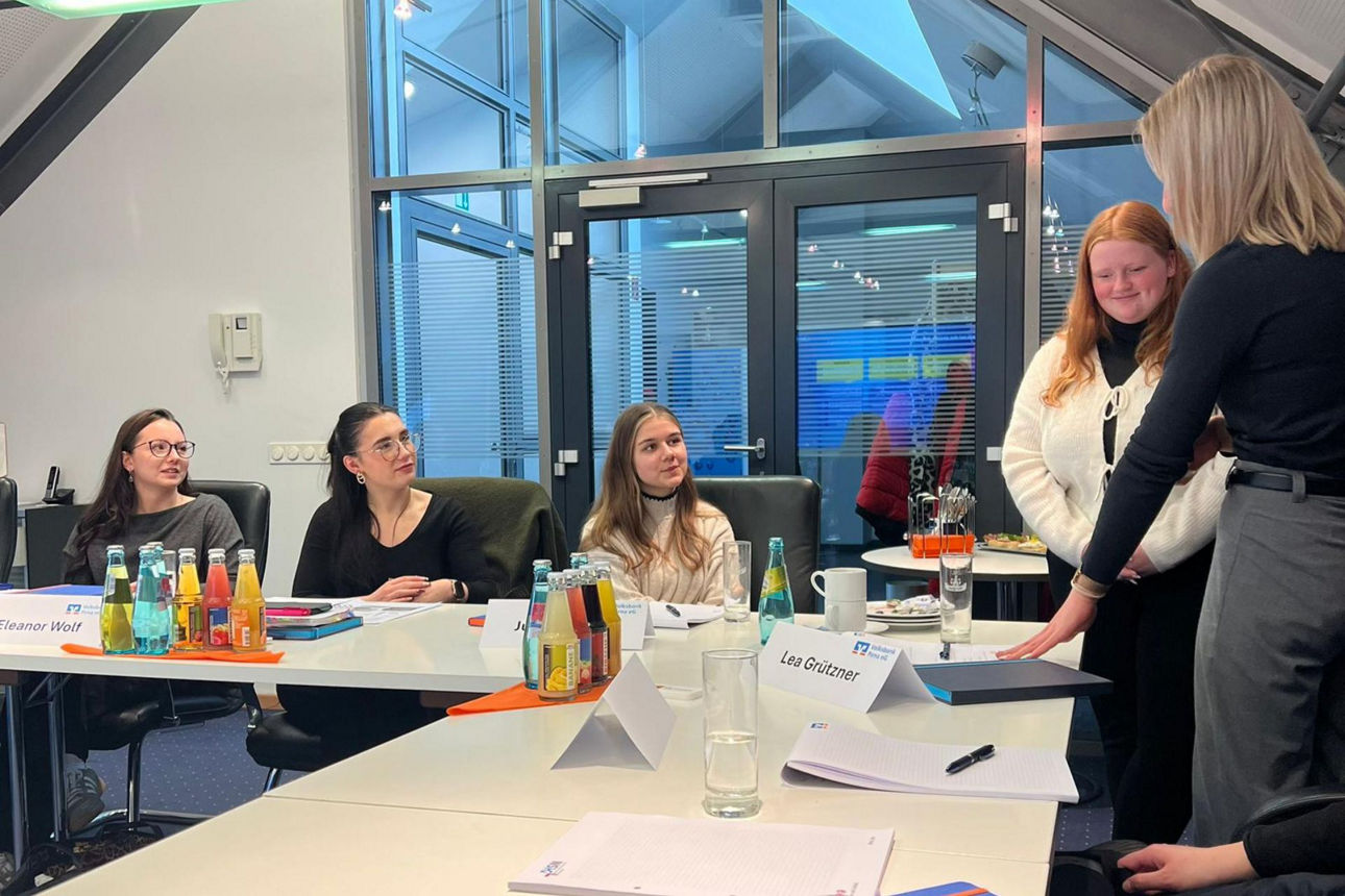 Auszubildende im Workshop bei der Gruppenarbeit im Gespräch, 3 Teilnehmerinnen sitzen und blicken zu zweien im Gespräch auf