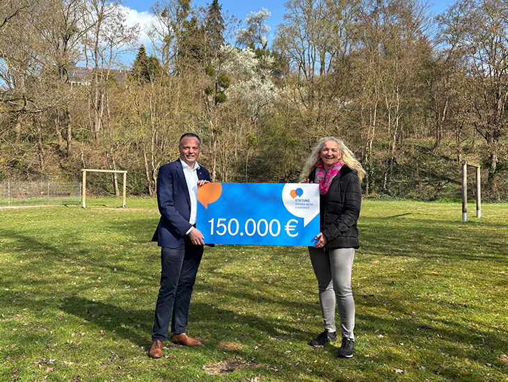 Symbolische Scheckübergabe auf einer Grünfläche