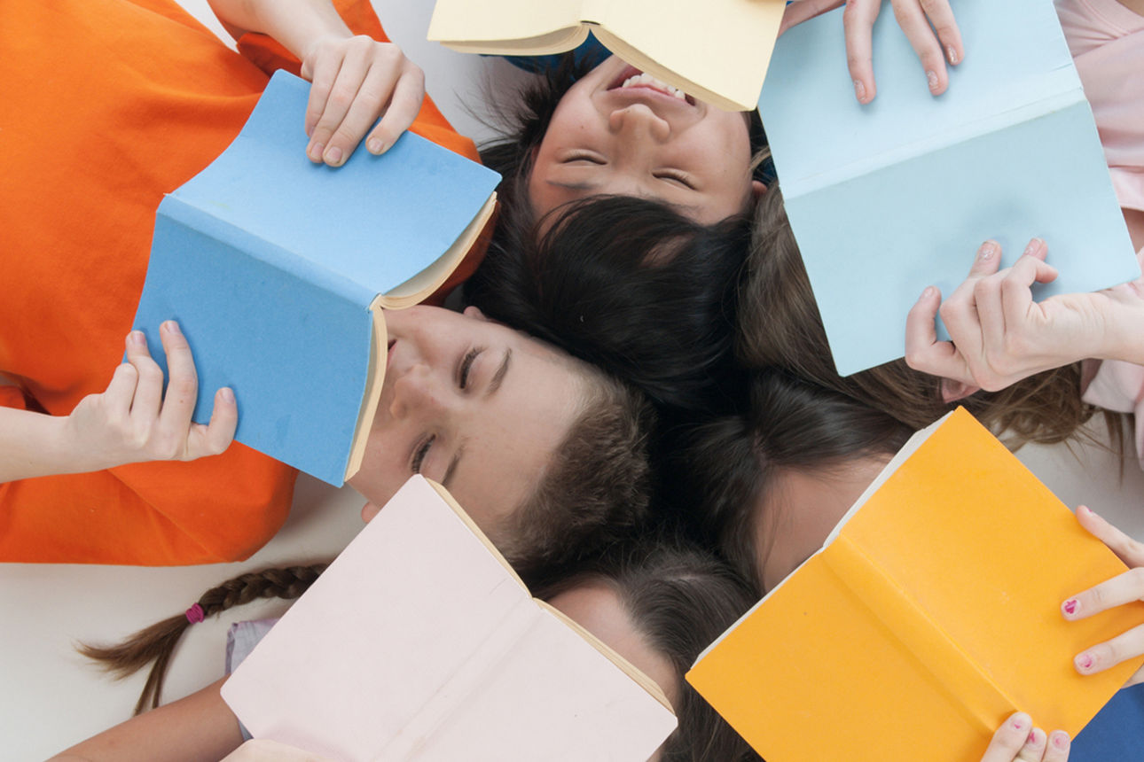 Jugendliche lesen auf dem Rücken liegend Bücher