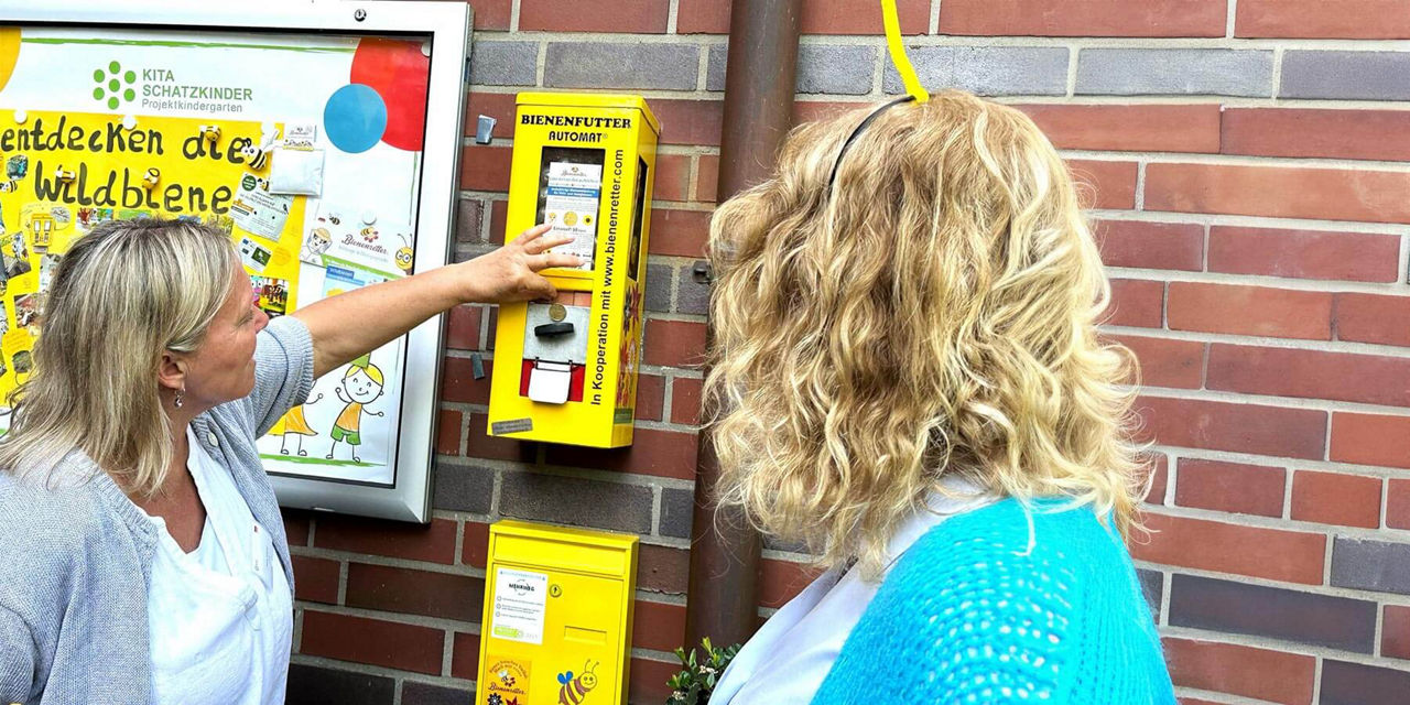 Zwei Frauen vor einem Bienenfutterautomat