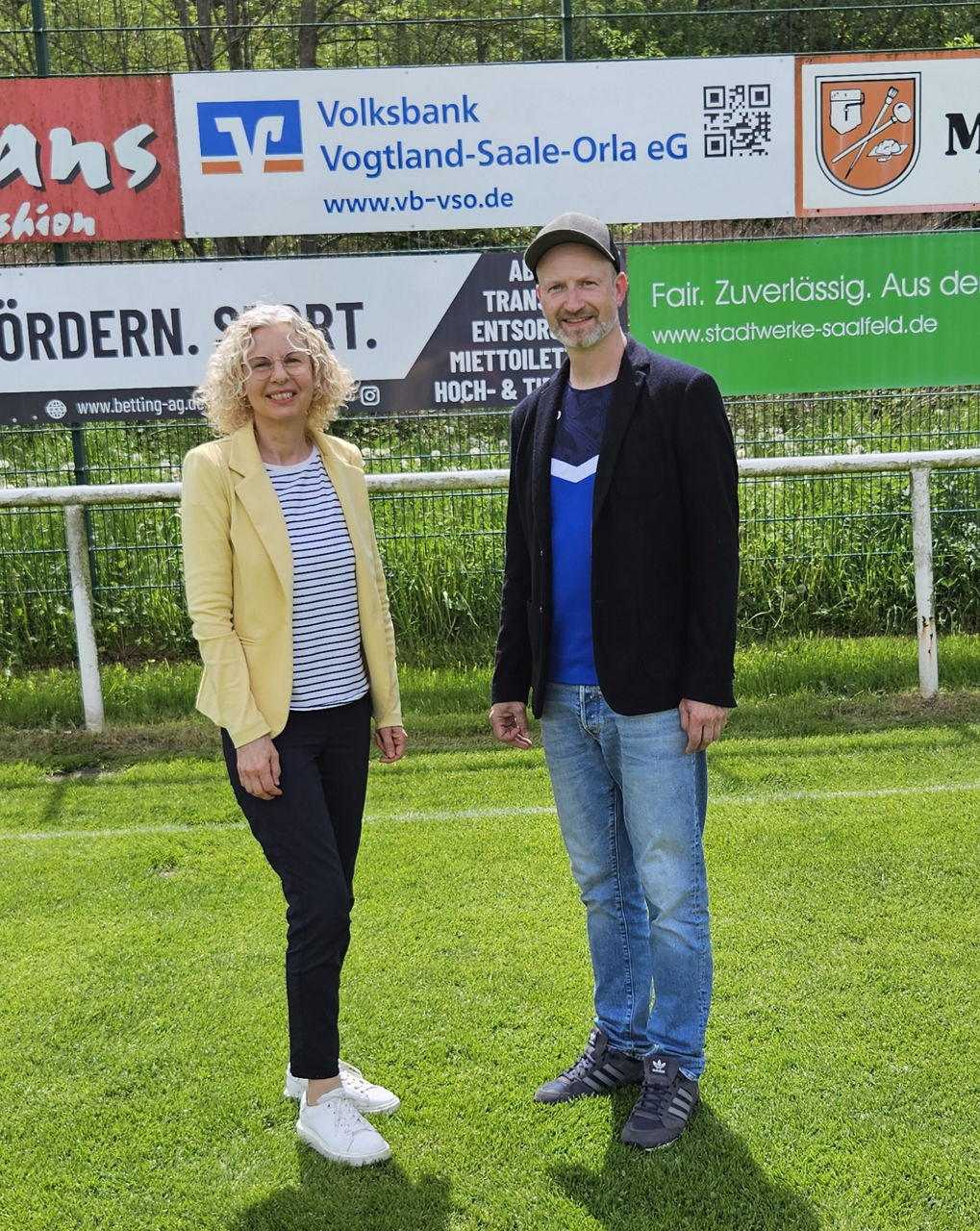 Christina Schwenck und Vereinsvorsitzender Rene Krumkamp vor der neuen Bandenwerbung