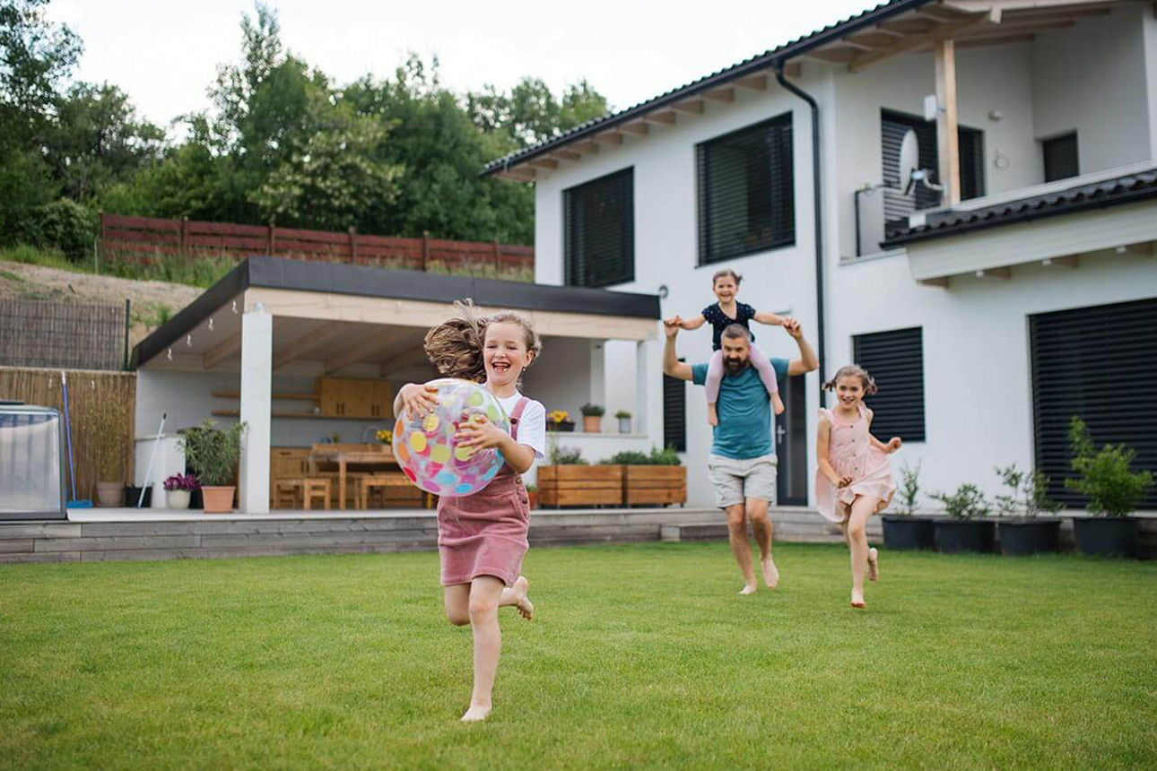 Junge Familie spielt im Garten ihres Einfamilienhauses