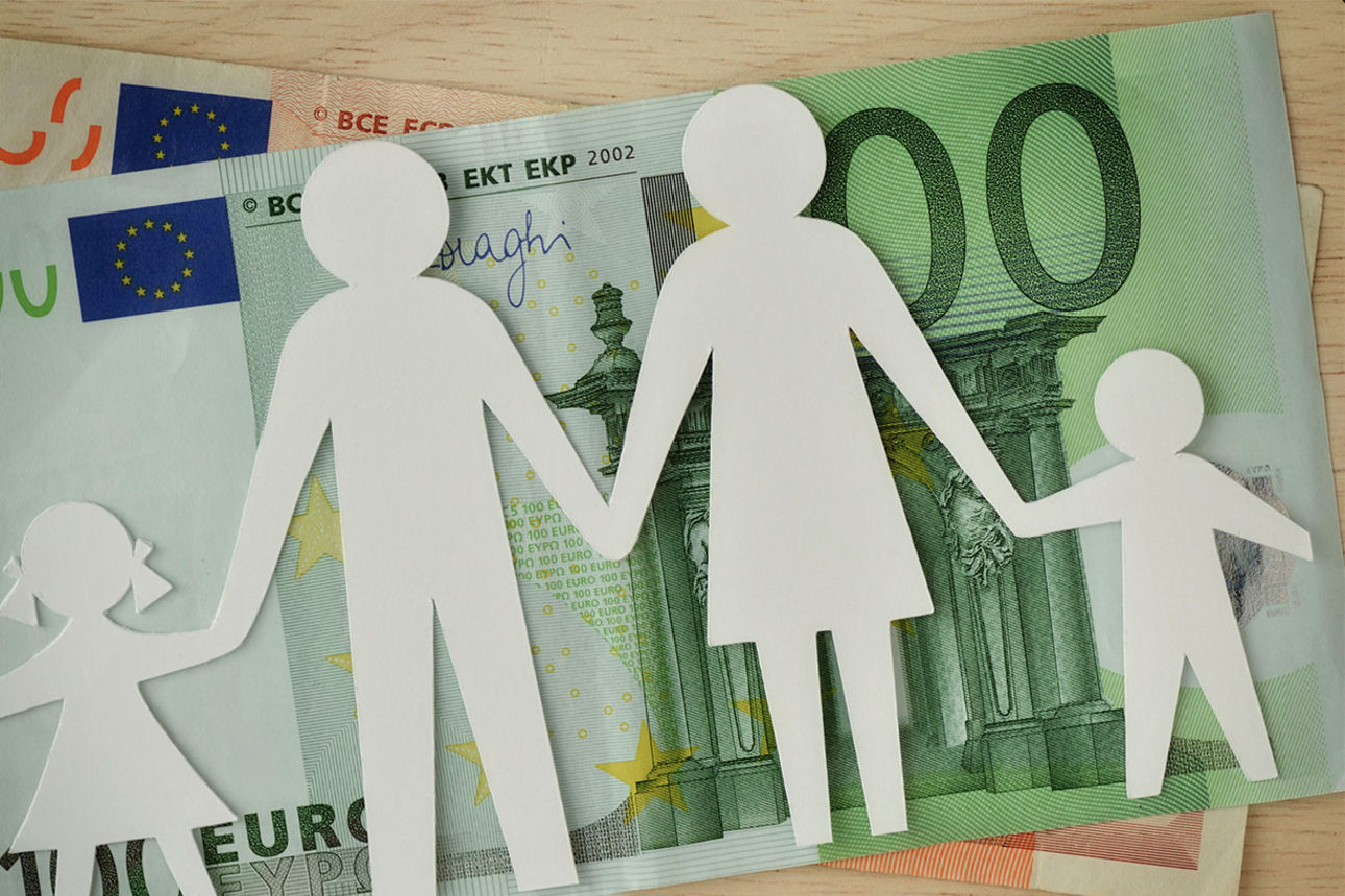 Ein Papierschnitt einer vierköpfigen Familie liegt auf Euro-Scheinen