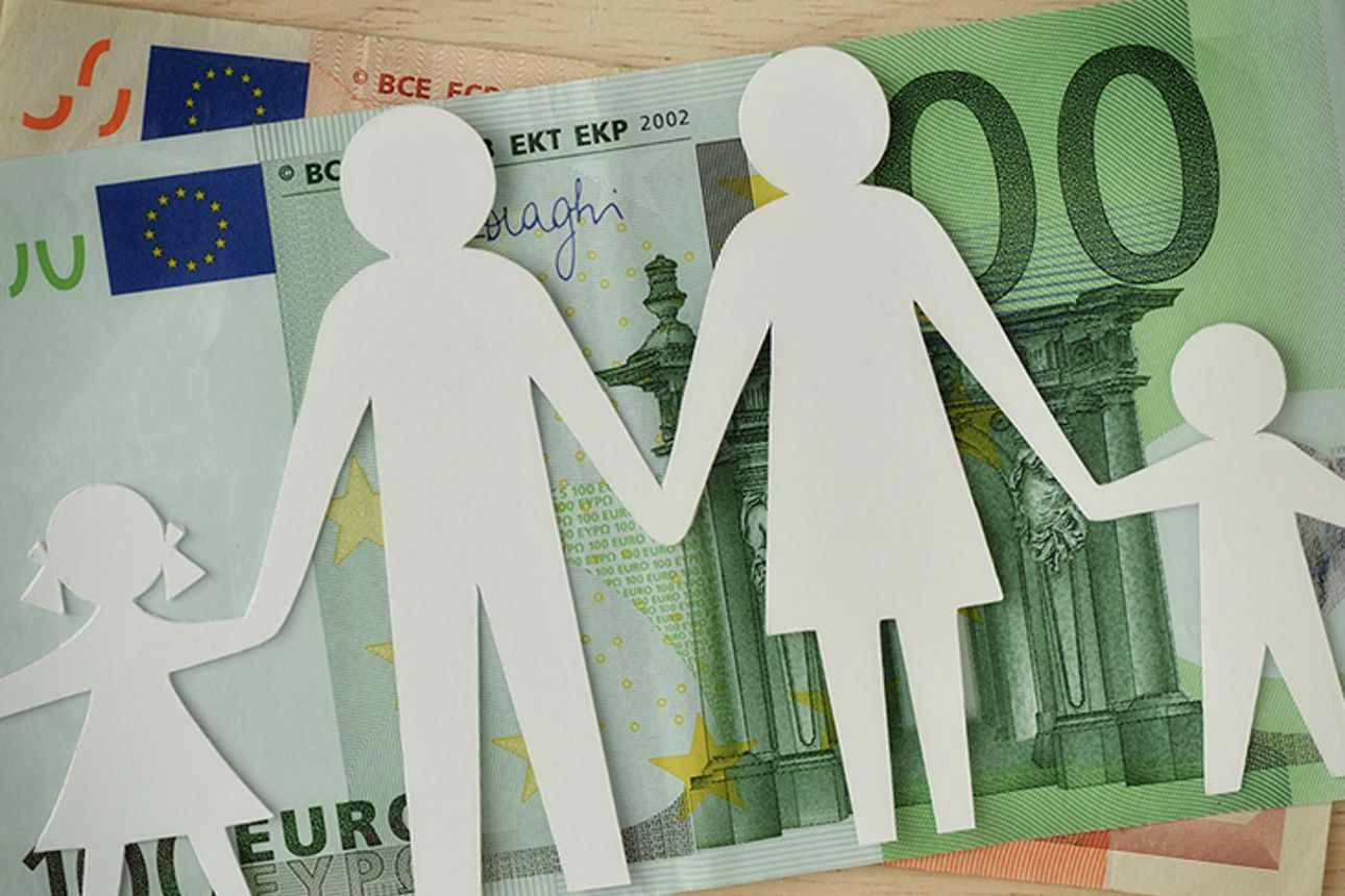 Ein Papierschnitt einer vierköpfigen Familie liegt auf Euro-Scheinen