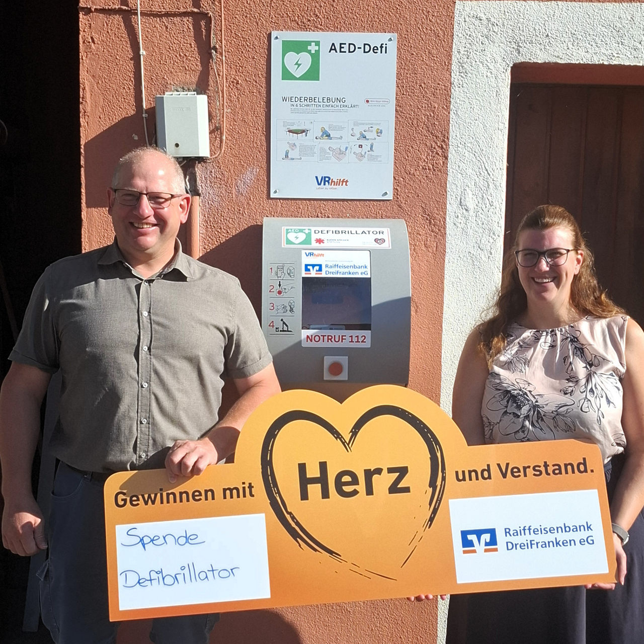 Klaus Faatz und Sabine Hofmann stehen vor einem Defibrillator