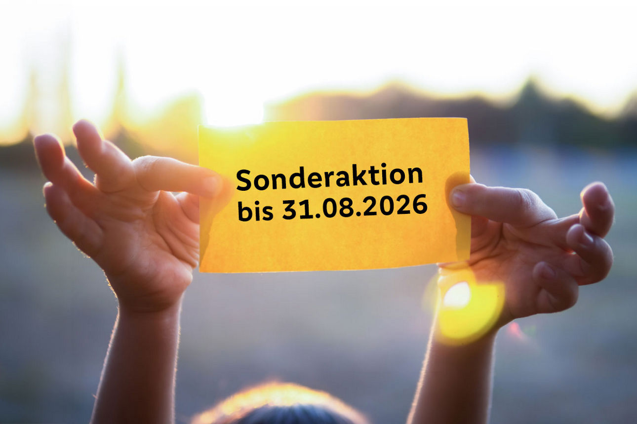 Ein Kind hält einen gelben Zettel mit der Aufschrift "Sonderaktion bis 31.08.2026" mit beiden Händen in die Luft